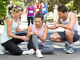 Woman with injured knee during race in park on a sunny day